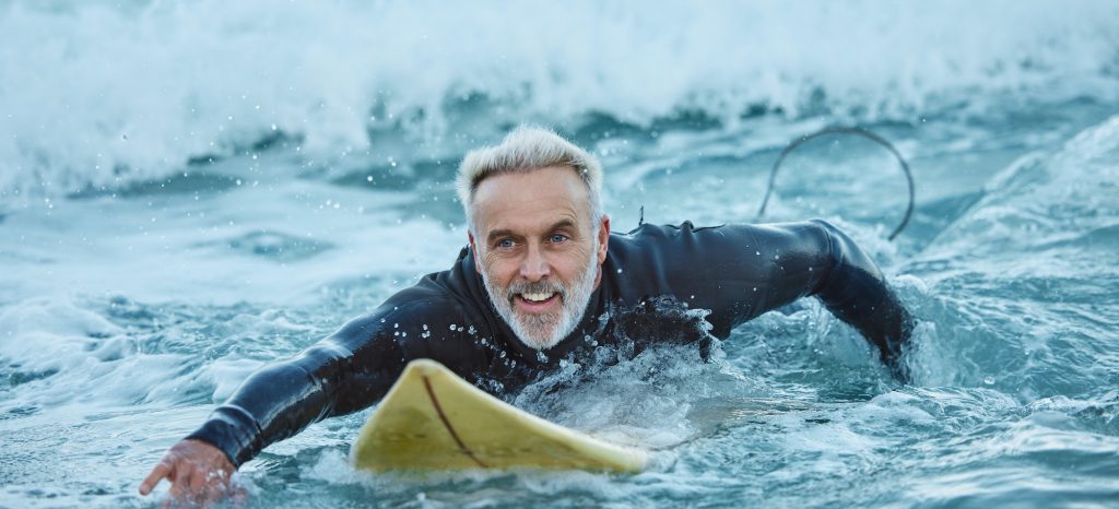 Surf, sea and sports with a mature man surfer in the water for sport, fitness and surfing during su