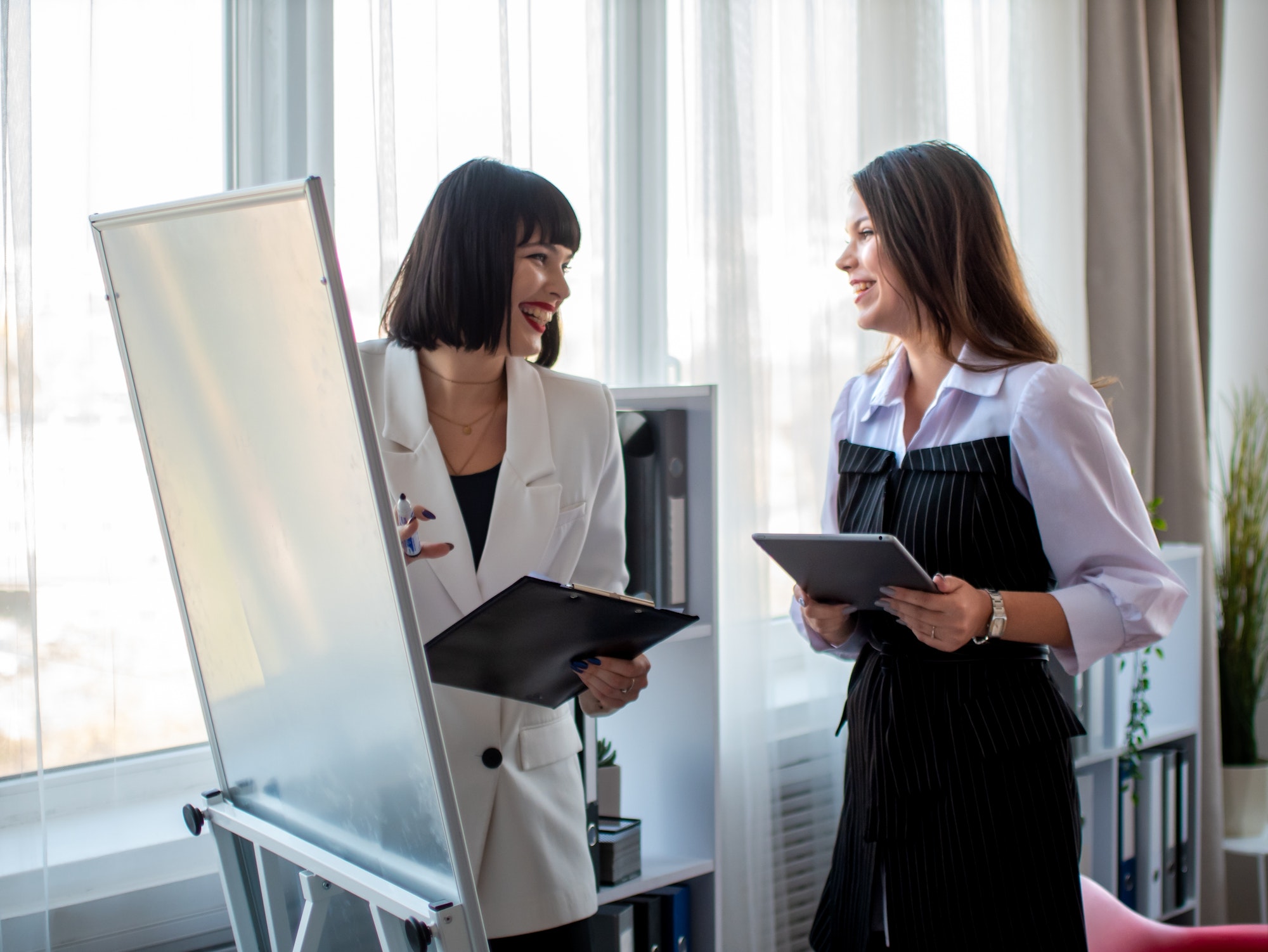 Business meeting in a bright office. Women showing charts on a white board